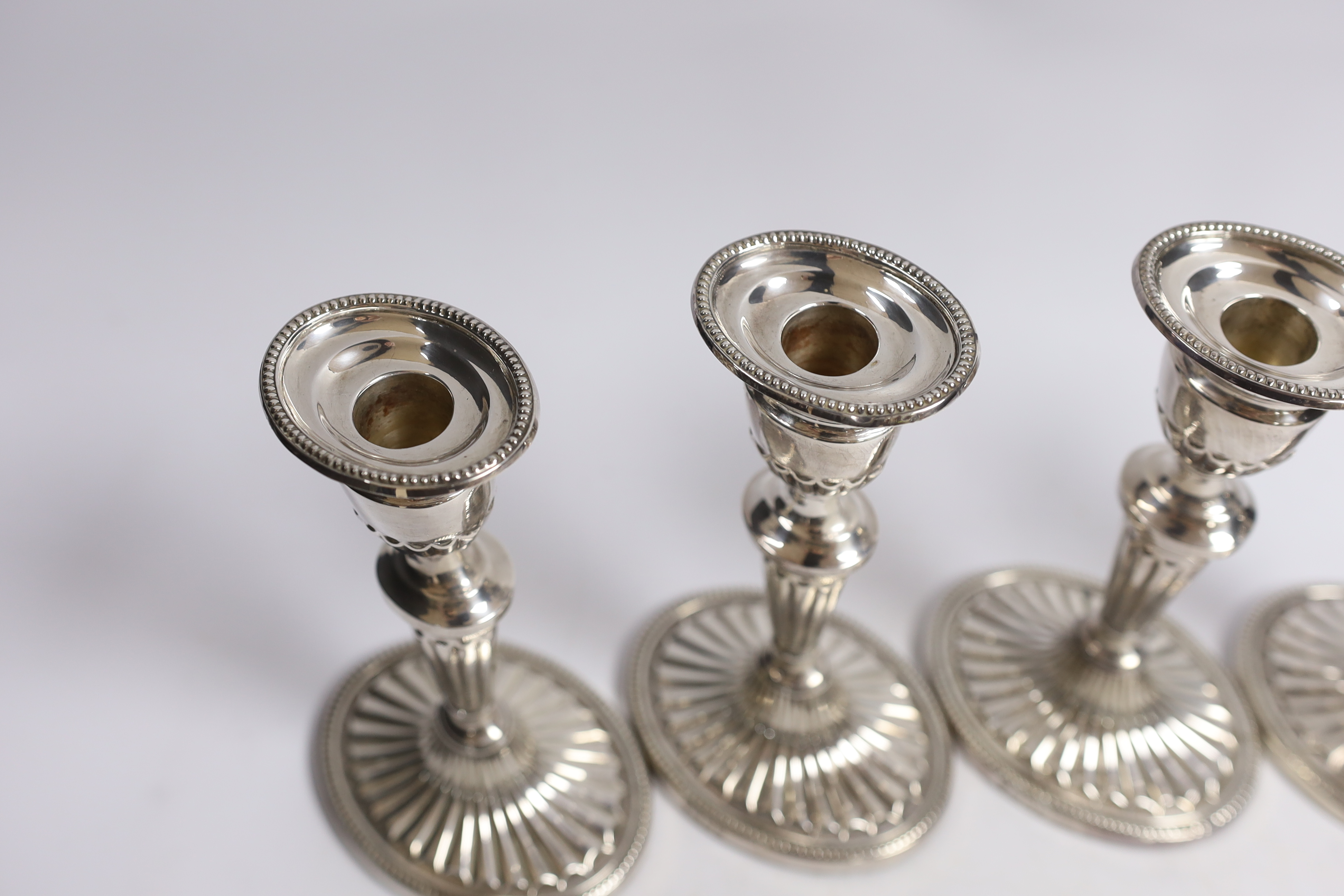 A set of four Elizabeth II silver candlesticks, with fluted stems and bases, C.J. Vander Ltd, London, 1973, 17.2cm, weighted.